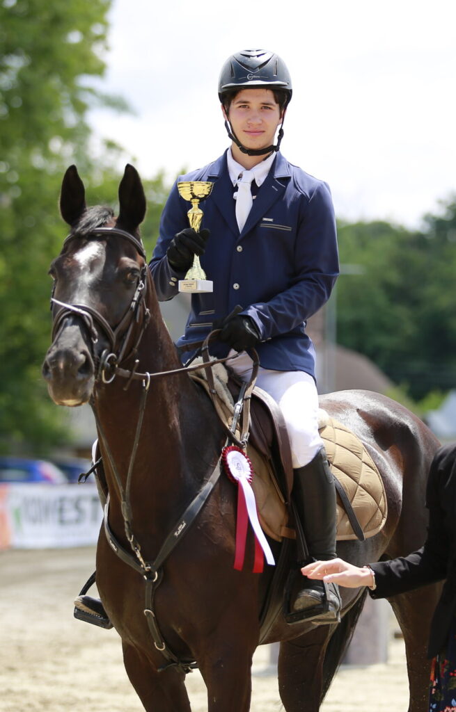 Egy lovas díjjal a kezében a fekete lovával egy versenyen
